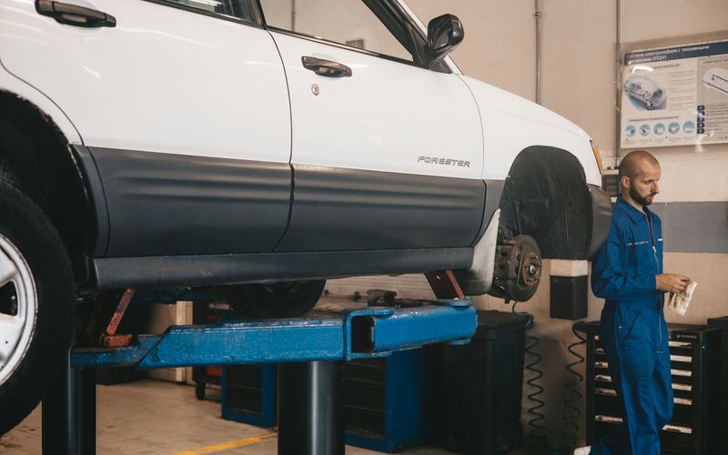 Mechanic evaluating a car on a lift for maintenance in an auto workshop
